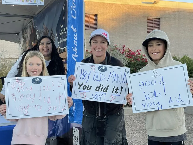 Four spectators holding up handmade signs for riders: "You did it!" and "good job".