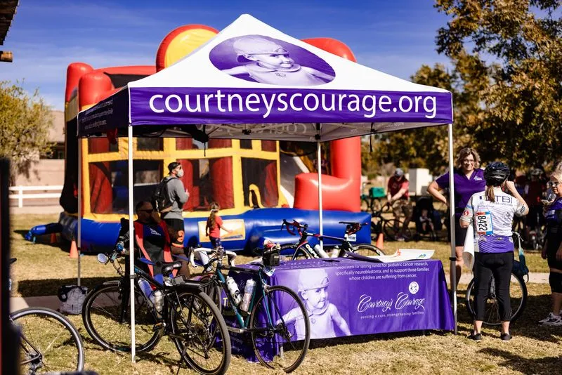 A nonprofit team tent with bikes racked outside and an inflatable slide beside it.