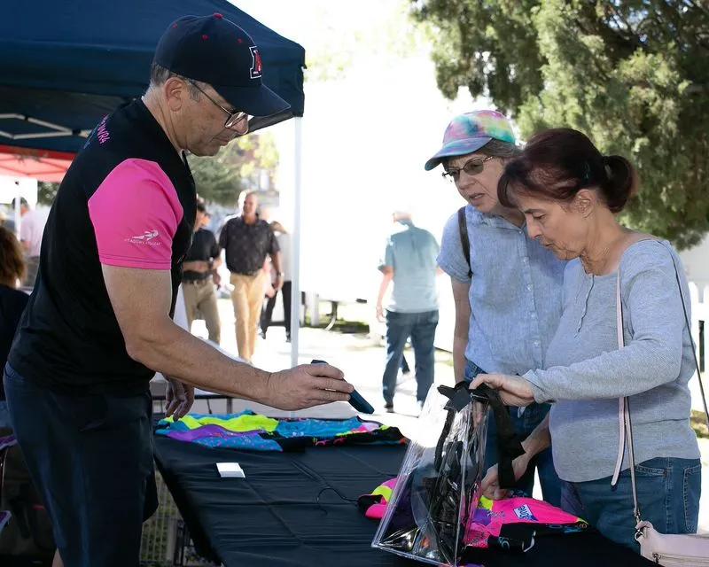 A vendor bagging apparel for two shoppers at an expo booth.