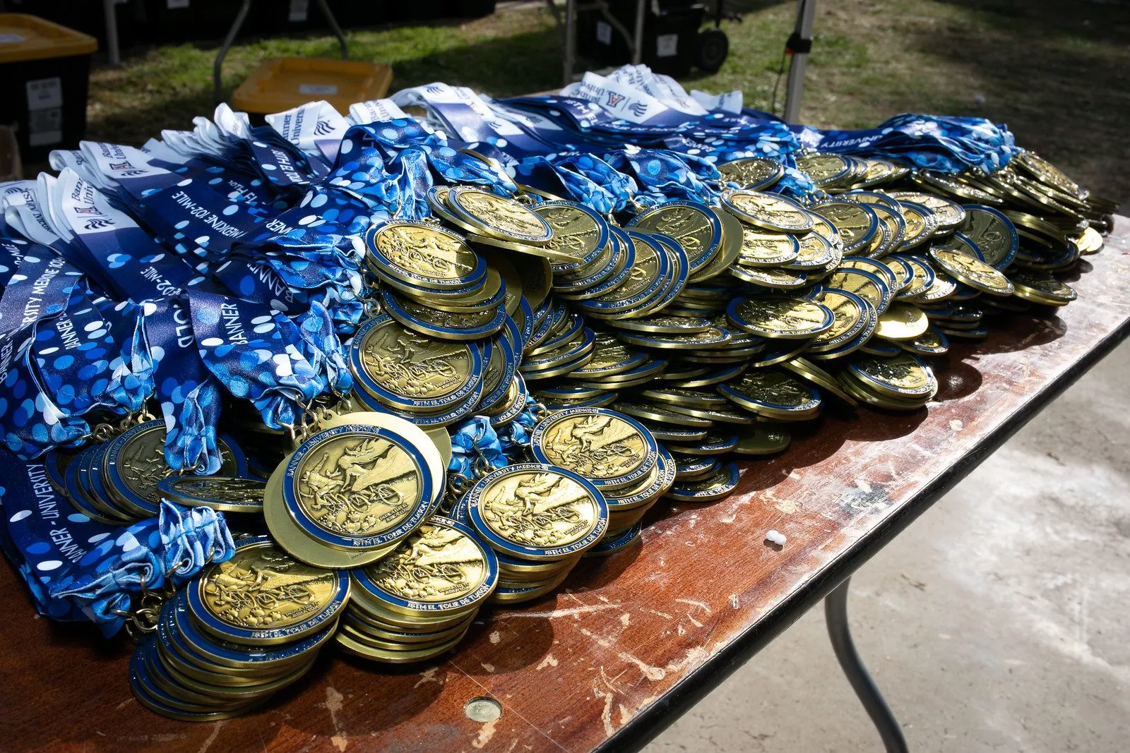 Hundreds of finisher medals heaped across a table.